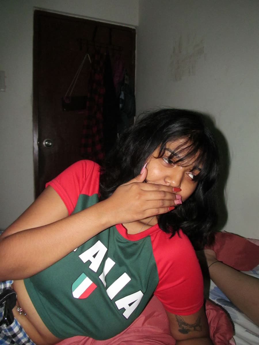 Anamika covering her smile in a green and red top