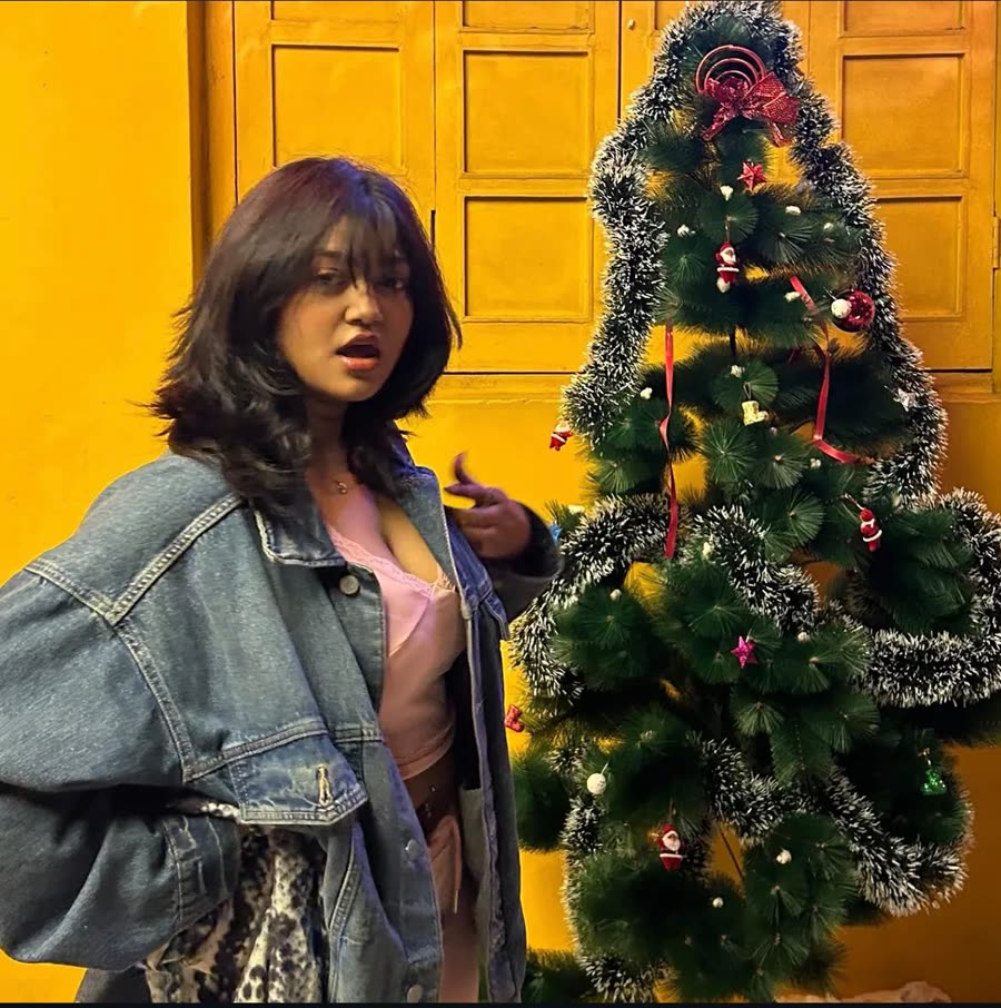 Anamika in a denim jacket beside a Christmas tree
